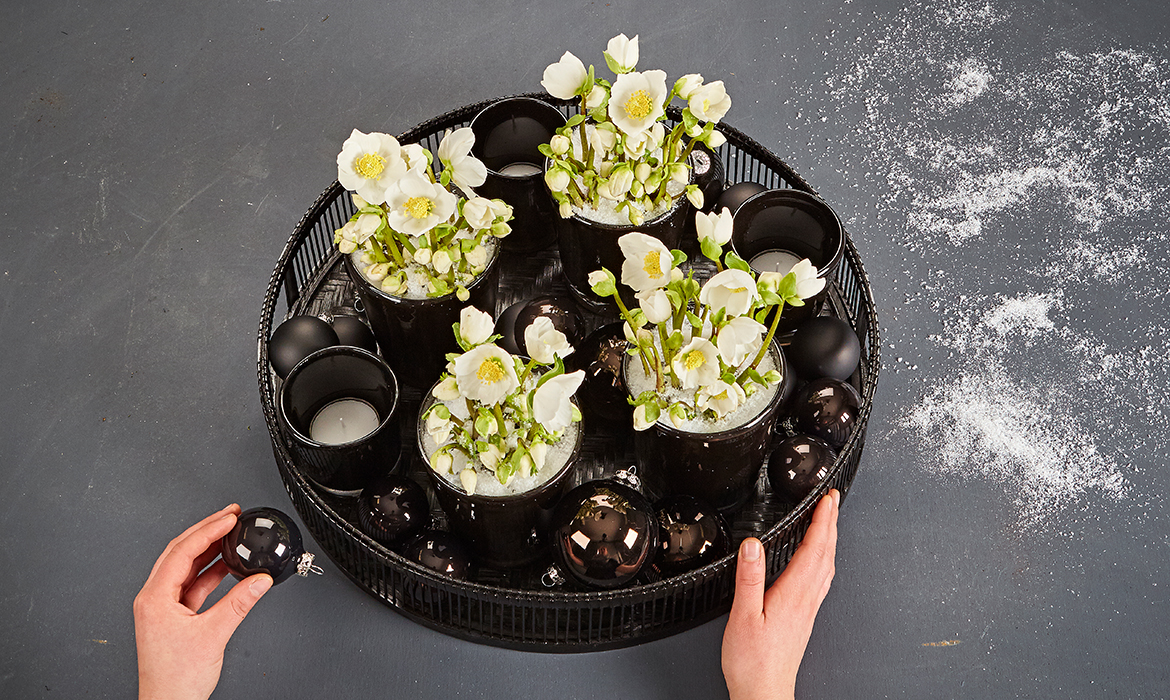 Arrange the Christmas Roses with black Christmas glitter balls and tea-light holders on the black tray.